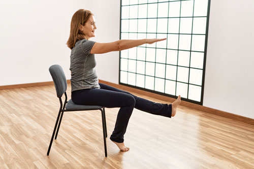 Woman sitting in a chair with leg and arm extended stretching