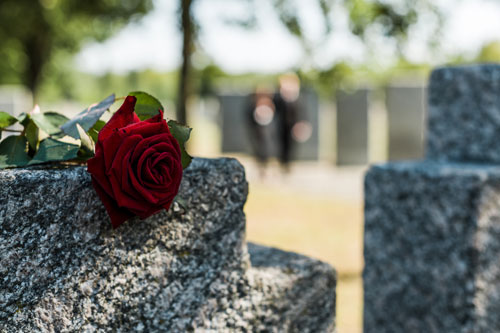 Photo of a red rose laying atop a gray gravestone