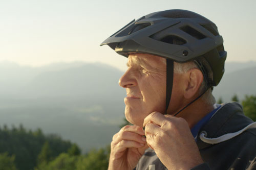 Image of older adult man buckling bike helmet