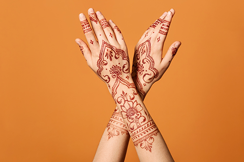Image of hands with henna art on an orange background