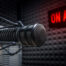 Microphone in a studio in front of a lit On Air sign