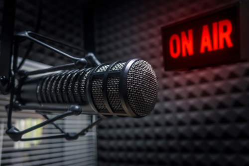 Microphone in a studio in front of a lit On Air sign