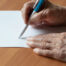 Close up of hands holding a pen writing on paper