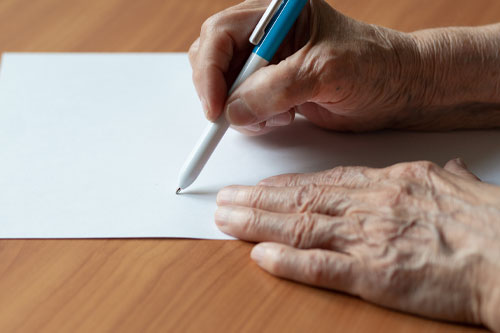 Close up of hands holding a pen writing on paper