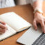 Person's hands on a laptop computer and writing in a journal