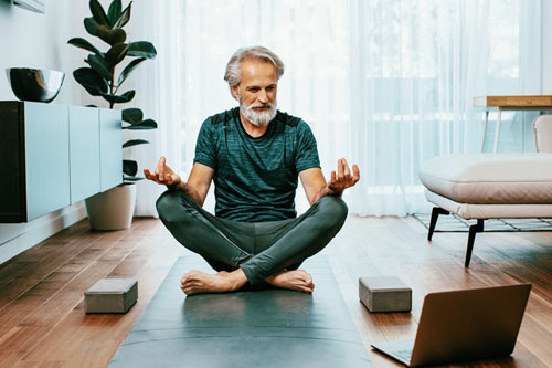 Man performing yoga with a laptop