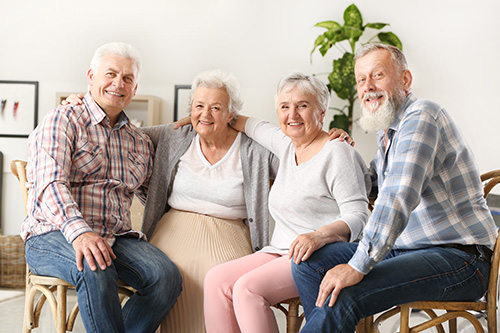 four elderly people sitting in a circle in a living room with a plant in the background