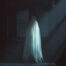 Eerie ghostly figure standing in the shadows of a dimly lit room