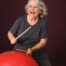 older woman happily drumming on medicine ball